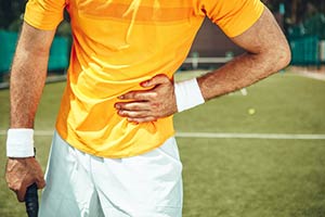 Photo of man playing tennis and experiencing rib pain